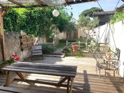 a wooden deck with two chairs and a swing at La maison de Marie - Jardin arboré - Garage privatif - Netflix in Carcassonne