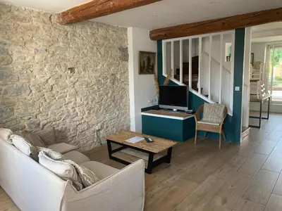 a living room with a couch and a tv and a stone wall at La maison de Marie - Jardin arboré - Garage privatif - Netflix in Carcassonne