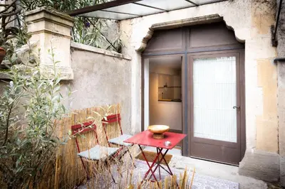 a red table and chairs in front of a door at Salut Le Petit Gite in Carcassonne