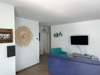 a living room with a blue couch and a tv at Tierra Del Viento - Villa Proche de la Mer in Peyriac-de-Mer