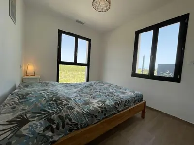a bedroom with a bed and two windows at Tierra Del Viento - Villa Proche de la Mer in Peyriac-de-Mer
