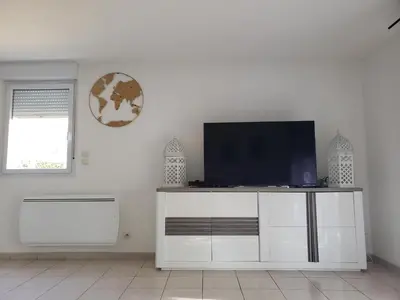 a living room with a tv on a white cabinet at les lys magiques in Carcassonne