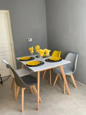 a dining table with yellow plates and glasses on it at Villa Reine du Sud proche des Grands Buffets in Narbonne