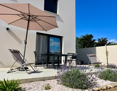 a patio with a table and chairs and an umbrella at La Maison Louis - moderne & familiale in Lapalme