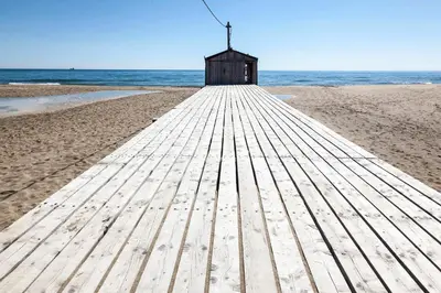a wooden boardwalk leading to a lifeguard shack on a beach at La Maison Louis - moderne & familiale in Lapalme