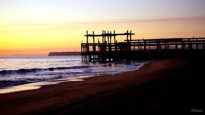 a wooden pier on the beach at sunset at La Maison Louis - moderne & familiale in Lapalme