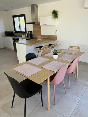 a kitchen with two wooden tables and pink chairs at La Maison Louis - moderne & familiale in Lapalme