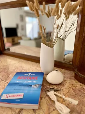 a book next to a vase and a computer mouse at La Maison Louis - moderne & familiale in Lapalme