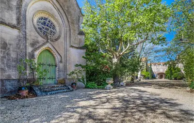 an old building with a green door and a tree at Amazing Home In Lézignan-Corbières in Lézignan-Corbières