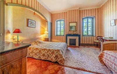 a bedroom with two beds and a fireplace at Amazing Home In Lézignan-Corbières in Lézignan-Corbières