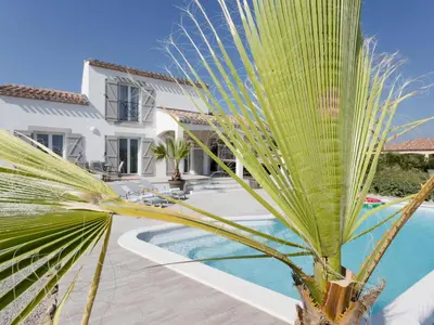 a palm tree in front of a house with a swimming pool at Luna in Aigne