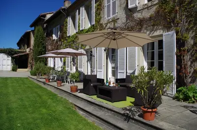 a patio with umbrellas and plants in front of a building at Chambres d'Hôtes Domaine du Hameau Baylesse in Saint-Jean-dʼAigues-Vives