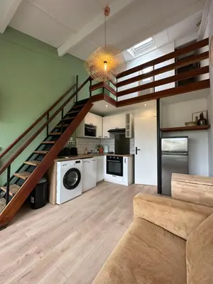 a living room with a staircase and a kitchen at La Mezza de Gruissan in Gruissan