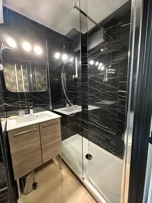 a black bathroom with a shower and a sink at La Mezza de Gruissan in Gruissan