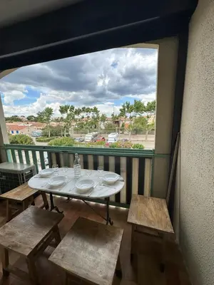 a table and chairs on a balcony with a window at La Mezza de Gruissan in Gruissan