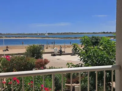 a view of a beach and the ocean with a balcony at Au bord de la plage du Grazel in Gruissan