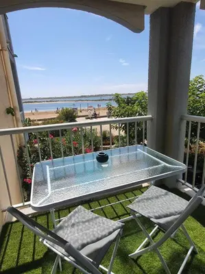 a table and chairs on a balcony with a view of the beach at Au bord de la plage du Grazel in Gruissan