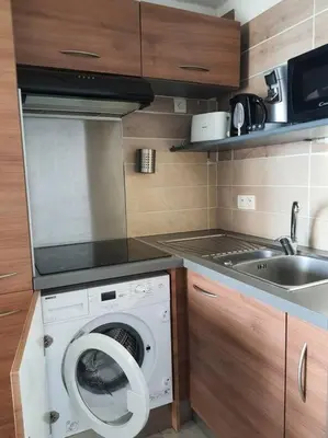 a kitchen with a washing machine and a sink at Au bord de la plage du Grazel in Gruissan