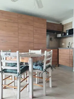 a kitchen with a glass table and two chairs at Au bord de la plage du Grazel in Gruissan