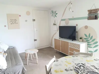 a living room with a table and a tv at Au bord de la plage du Grazel in Gruissan