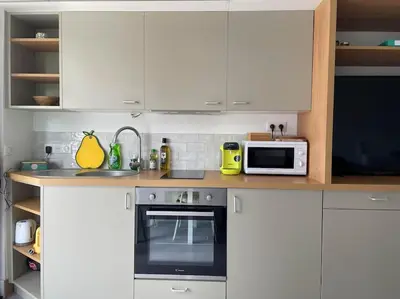 a kitchen with white cabinets and a stove and a microwave at Studio - Centre de Villefranche de Lauragais in Villefranche-de-Lauragais
