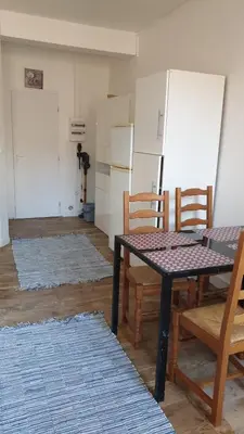 a kitchen with a table and chairs and a refrigerator at Appartements simples et fonctionnels in Pamiers