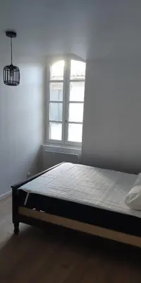 a bed in a room with a window at Appartements simples et fonctionnels in Pamiers