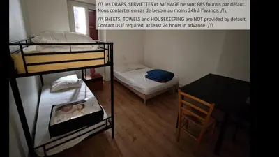 a room with two bunk beds and a table and a chair at Appartements simples et fonctionnels in Pamiers
