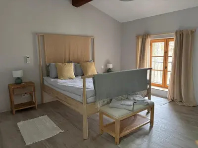 a bedroom with a bed and a chair and a window at Hidden Oasis - Maison de caractère avec piscine in Azille