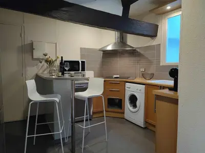 a kitchen with two stools and a counter with a washing machine at Charme de Victor ConciergerieDameCarcas in Carcassonne