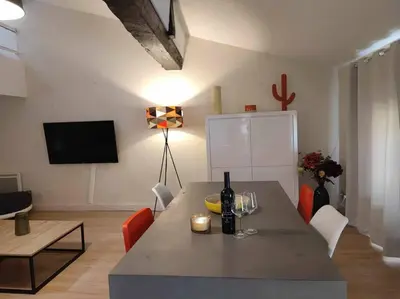 a living room with a table with a bottle of wine at Charme de Victor ConciergerieDameCarcas in Carcassonne