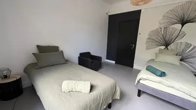 a bedroom with two beds and a chair in it at Chambre Ginkgo au Domaine de l'Aven in Villeneuve-Minervois