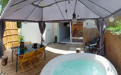 a patio with a hot tub and a table and chairs at L'Entre Nous à Carcassonne in Carcassonne