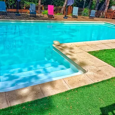 a swimming pool with blue water in a yard at L'Entre Nous à Carcassonne in Carcassonne