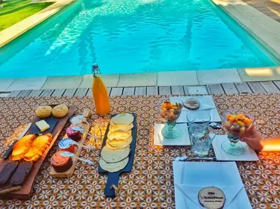 a table with food and drinks next to a swimming pool at L'Entre Nous à Carcassonne in Carcassonne