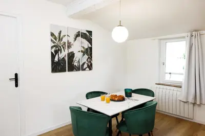 a dining room with a white table and green chairs at Le T2 Chic ! in Carcassonne