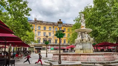 a fountain in a plaza with people walking by a building at Le T2 Chic ! in Carcassonne