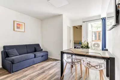 a living room with a couch and a table and chairs at Côté Palais avec Climatisation - Fibre & Netflix - Spacieux en rez-de-chaussée in Carcassonne