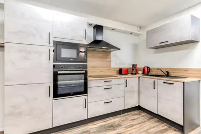 a kitchen with stainless steel appliances and wooden floors at Côté Palais avec Climatisation - Fibre & Netflix - Spacieux en rez-de-chaussée in Carcassonne