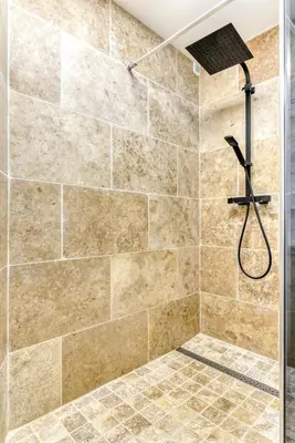 a bathroom with a shower with a stone wall at Côté Palais avec Climatisation - Fibre & Netflix - Spacieux en rez-de-chaussée in Carcassonne