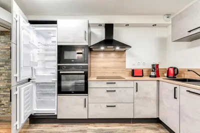 a kitchen with white cabinets and an open refrigerator at Côté Palais avec Climatisation - Fibre & Netflix - Spacieux en rez-de-chaussée in Carcassonne
