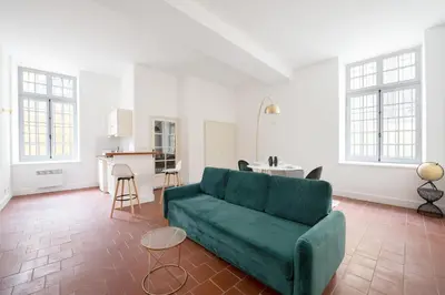 a living room with a green couch and a kitchen at superbe appartement avec cour dans la bastide in Carcassonne