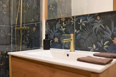 a bathroom with a sink and a black and gold wallpaper at superbe appartement avec cour dans la bastide in Carcassonne