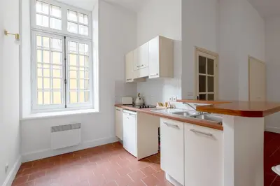 a kitchen with white cabinets and a sink and a window at superbe appartement avec cour dans la bastide in Carcassonne