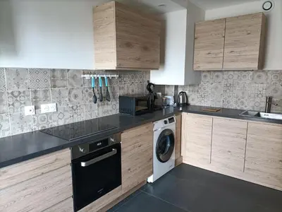 a kitchen with wooden cabinets and a washer and dryer at Le Rubis in Gruissan