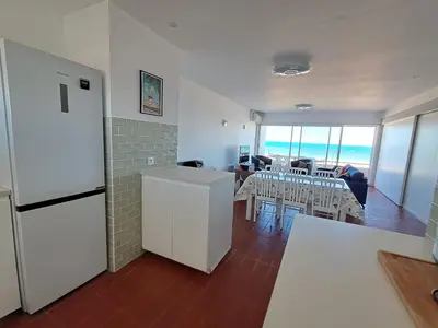 a kitchen with a white refrigerator and a dining room at Le Front de mer - vue imprenable in Port-la-Nouvelle