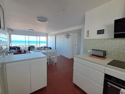 a kitchen with white cabinets and a dining room with the ocean at Le Front de mer - vue imprenable in Port-la-Nouvelle