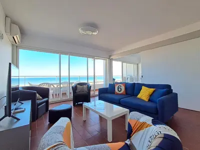a living room with a blue couch and a tv at Le Front de mer - vue imprenable in Port-la-Nouvelle