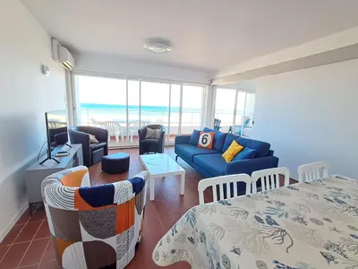 a living room with a blue couch and a table at Le Front de mer - vue imprenable in Port-la-Nouvelle