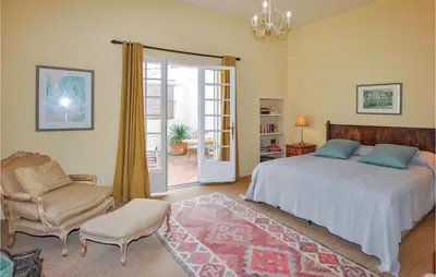 a bedroom with a bed and a chair and a window at Amazing Home In Thézan-Des-Corbières in Thézan-des-Corbières